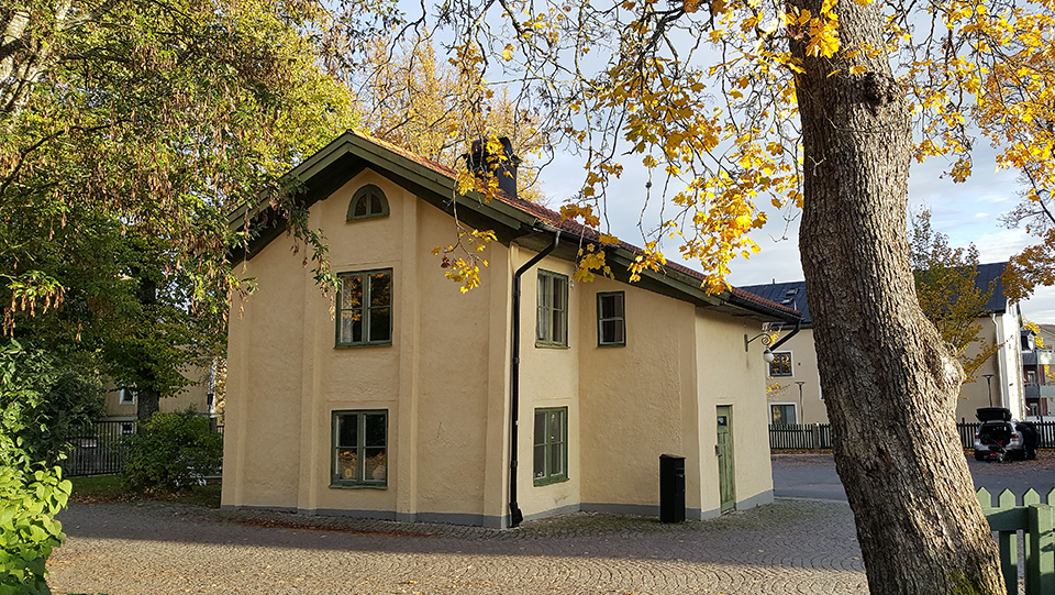 Grindstugan vid Kristineberg. Ett gult hus med träd i höstfärger runt om. Foto.